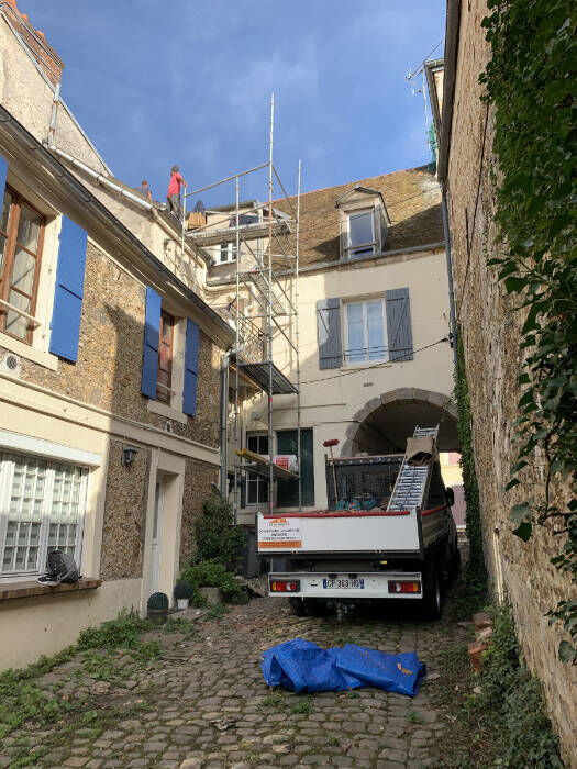 Chantier de couverture avec échafaudage dans une ruelle pavée d’un village des Yvelines