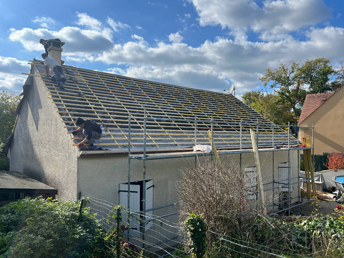 Couvreurs en train de poser le liteaunage neuf d’un pavillon avant la pose des tuiles