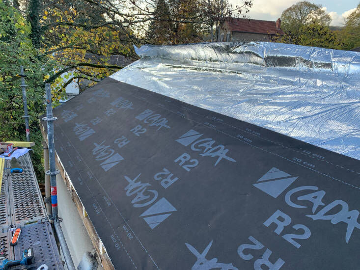 Pose de l’écran de sous-toiture sur un pan de toit en cours de rénovation
