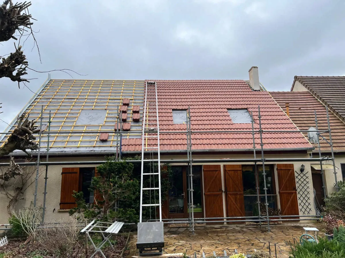 Toiture à mi-chantier : tuiles rouges neuves posées sur la moitié du pan d’une maison des Yvelines