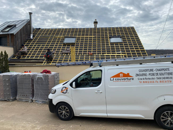 Livraison de palettes de tuiles sur un chantier de remplacement de toiture, camion LJ Couverture devant la maison