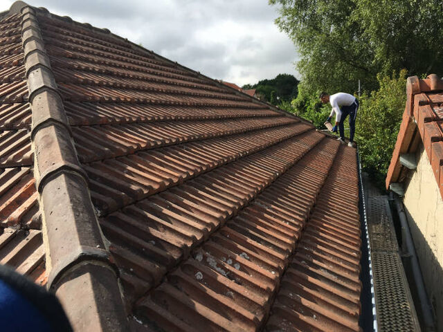 Couvreur remplaçant des tuiles sur une toiture dans les Yvelines