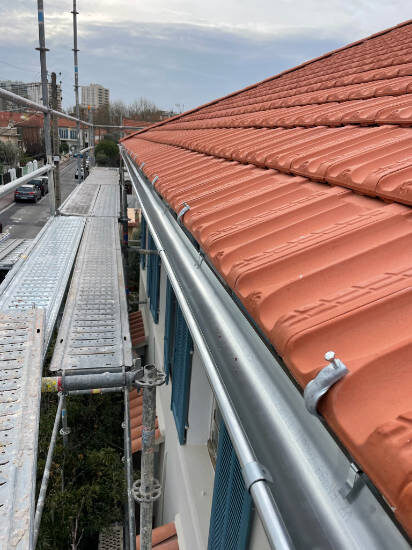 Toiture en tuiles rouges neuves vue depuis le faîtage après rénovation