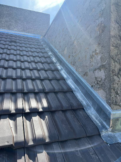 Tuiles plates anthracite et détail de zinguerie sur une toiture rénovée