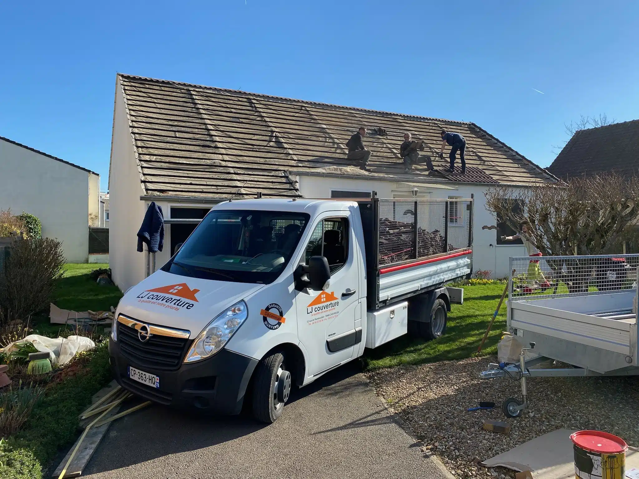 Un Camion de LJ Couverture - devannt un pavillon, une équipe de couvreur entrain d'effectuier un remplacement de toiture à Chevreuse